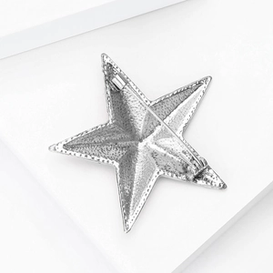 Back view of silver star brooch with grainy texture and secure safety pin closure