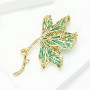 Detailed close-up of golden lotus leaf brooch with green enamel and white pearl accents