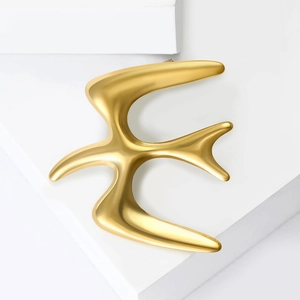 Elegant gold swallow bird brooch pin in a minimalist design on white stone blocks