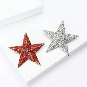 Vintage star brooches with sparkling red and white rhinestones on white display stands