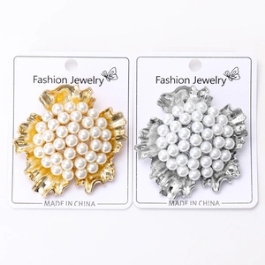 Detail of flower brooch featuring white pearls and wavy gold and silver metal petals