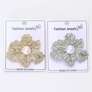 Détail de broches en forme de feuilles dorées et argentées avec strass et perles