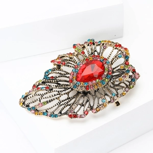 Macro detail of retro hollow brooch with large red teardrop gemstone and colorful crystals
