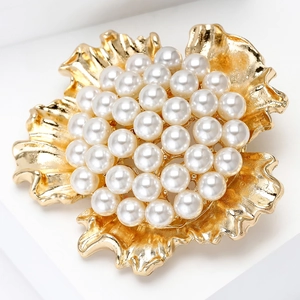 Macro shot of elegant golden flower brooch with delicate pearls and wavy petal texture