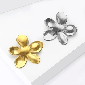 Minimalist liquid metal flower brooches in gold and silver finish on a white display