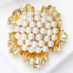 Detailed macro view of an elegant golden flower brooch featuring round white pearls