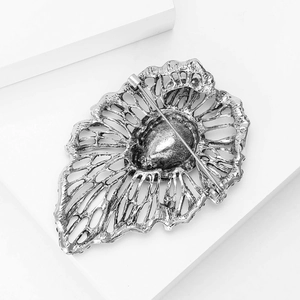 Macro detail of retro hollow silver alloy brooch showing intricate metal textures and secure pin