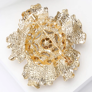 Macro detail of the gold flower brooch back showing textured metal and safety pin