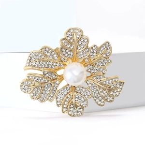 Broche fleur dorée élégante avec perle blanche et strass brillants sur un support blanc