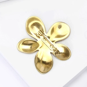 Back view of gold stainless steel flower brooch with liquid metal finish and safety pin