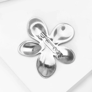 Detailed back view of silver flower brooch showing the secure pin fastener and metal finish