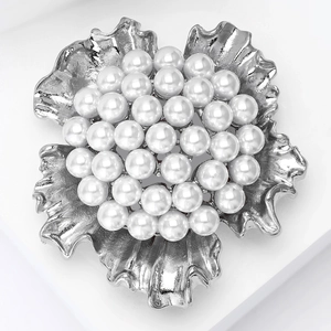 Detailed view of elegant silver flower brooch with multiple white pearls on petals