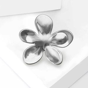 Macro detail of a silver liquid metal flower brooch with polished finish and smooth curves