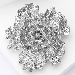 Detail view of the silver flower brooch back featuring hammered texture and safety pin