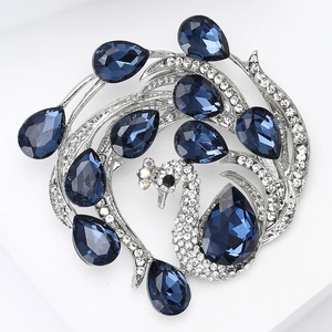 Detailed macro view of a silver peacock brooch with deep blue pear-shaped rhinestones