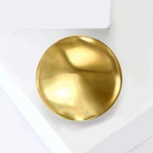 Minimalist round liquid metal brooch with wavy texture on a modern geometric display