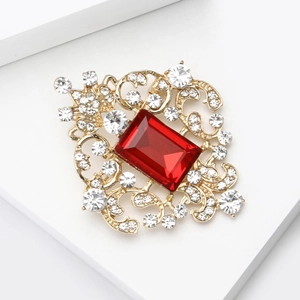 Detailed close-up of a vintage gold brooch with large red gemstone and filigree details