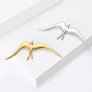 Spille a forma di uccello in oro e argento su gradini geometrici bianchi minimalisti