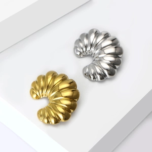 Polished gold and silver C-shaped croissant earrings on white geometric stands