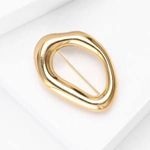 Gros plan détaillé d'une broche dorée de style liquide sur un présentoir blanc chic