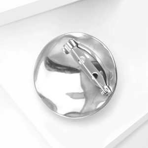 Macro shot of silver liquid metal brooch back with secure safety pin and rotating clasp lock