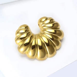 Macro shot of gold croissant-style stainless steel earring with polished ribbed texture