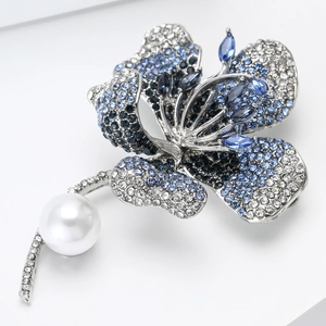 Close-up of elegant hibiscus flower brooch with blue gradient rhinestones and a large pearl