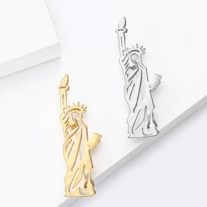 Broches Statue de la Liberté minimalistes en finitions or et argent sur présentoir blanc
