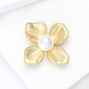 Elegant gold flower brooch with a large white pearl and brushed metal texture
