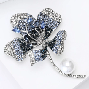 Close-up of luxury flower brooch featuring blue crystals and a large white round pearl