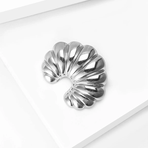 Macro detail of silver stainless steel C-shaped brooch with radial pleated texture