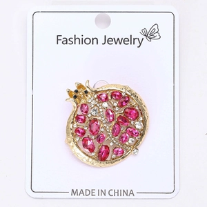 Détail d'une broche grenade avec cristaux roses et diamants sur une base dorée élégante