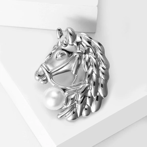 Détail d'une broche tête de cheval argentée ornée d'une grande perle blanche élégante