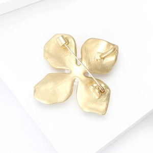 Back view of gold matte alloy four-petal flower brooch with pin buckle and brushed texture