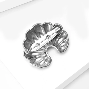 Polished silver croissant brooch pin with minimalist shell-like texture and secure clasp