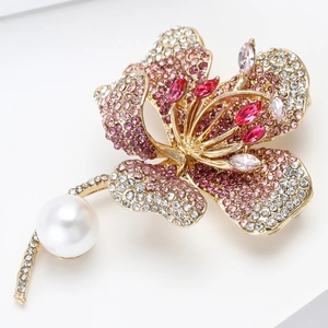 Close-up of luxury hibiscus flower brooch with pink crystals and a large white pearl