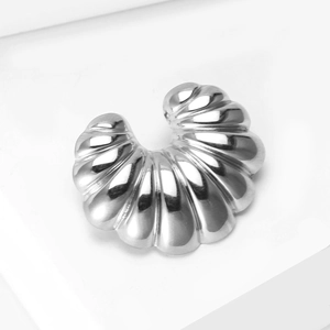 Macro shot of silver croissant-style stainless steel brooch with polished ribbed texture