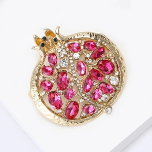 Élégante broche grenade dorée avec cristaux roses sur support d'exposition blanc