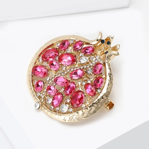 Élégante broche grenade dorée avec pierres roses et pavé de cristaux sur fond blanc
