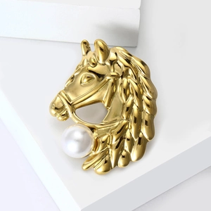 Detailed close-up of a gold horse head brooch with a large white pearl on a white stand