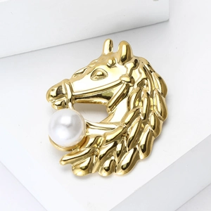 Macro detail of a golden horse head brooch with a white pearl accent and fine metallic texture