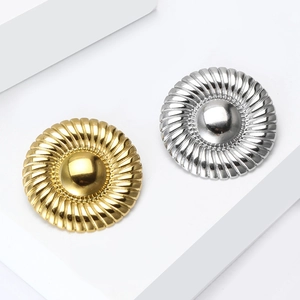 Detail view of round gold and silver stainless steel brooches with spiral texture