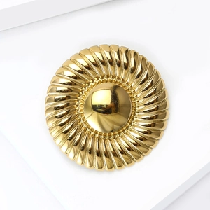 Macro detail of luxury golden round brooch featuring radial textures and metallic luster