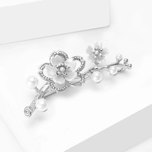 Dettaglio ravvicinato di una spilla a bouquet floreale con petali bianchi, perle e strass