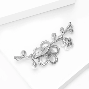 Dettaglio ravvicinato della spilla fiore di prugno in argento con perle e design cavo