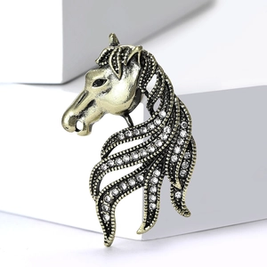 Vintage horse head brooch in antique gold finish with crystal accents on a white block