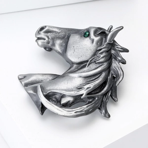 Vue détaillée d'une broche tête de cheval argentée avec crinière et strass vert brillant