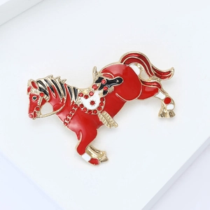 Macro shot of a red enamel horse brooch with sparkling rhinestones and gold-tone details