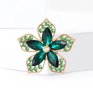 Broche fleur à cinq pétales dorée avec cristaux émeraude profonds et strass scintillants