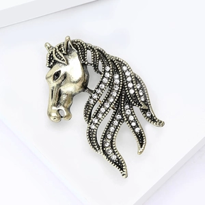 Macro detail of vintage horse head brooch with sparkling rhinestones on an antique gold finish
